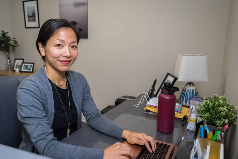 Dr. Gracie Yeo sits at her laptop.