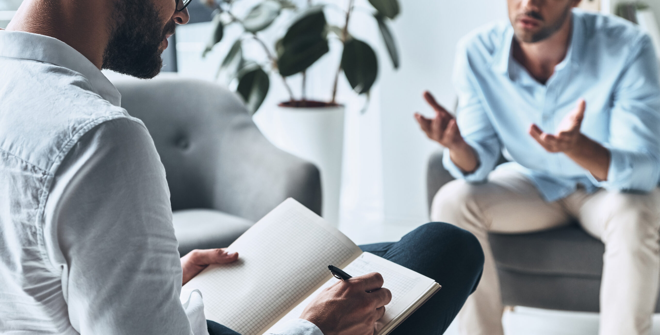 Psychiatrist takes notes while listening to a patient.
